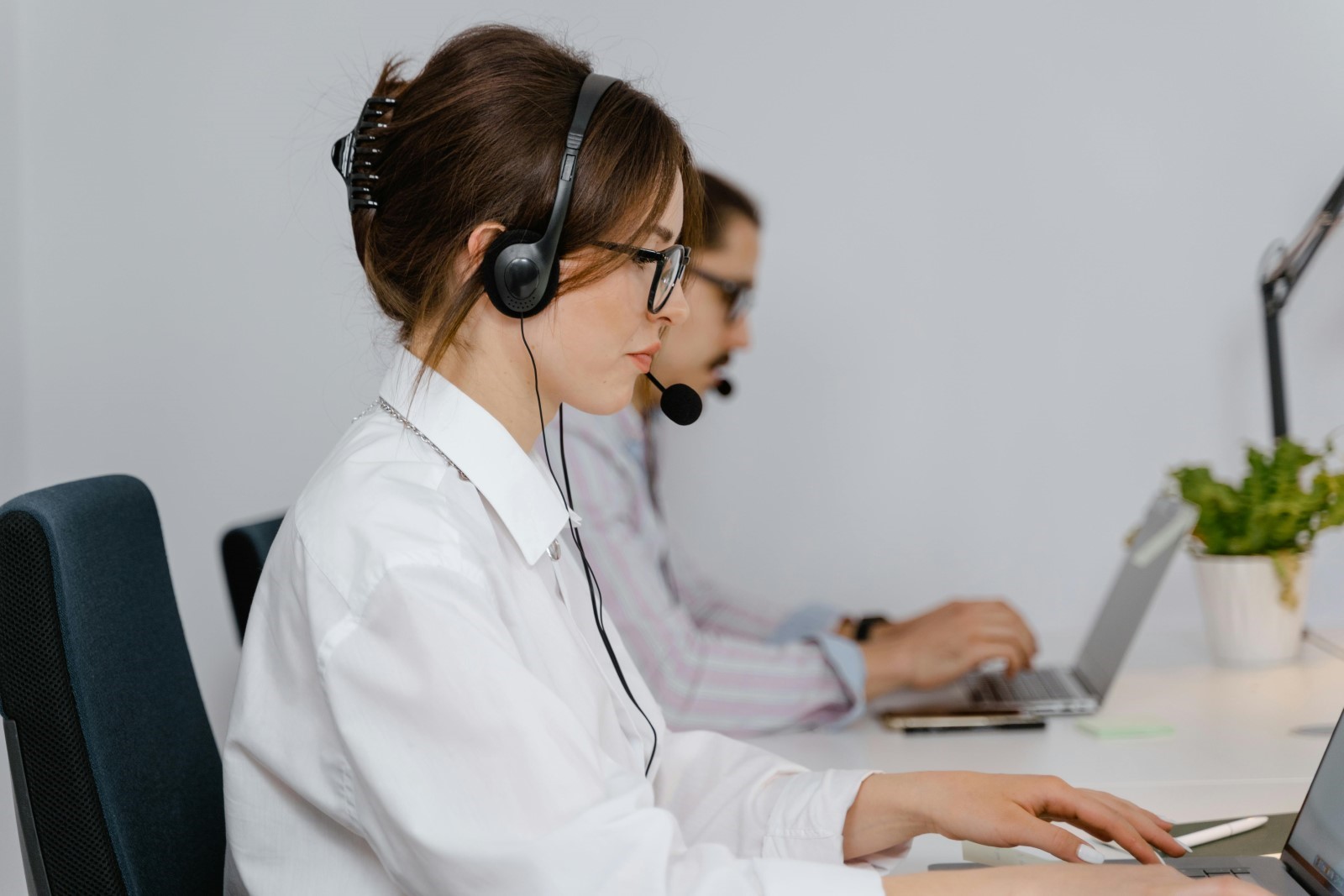 Customer service reps wearing headsets, working on laptops 